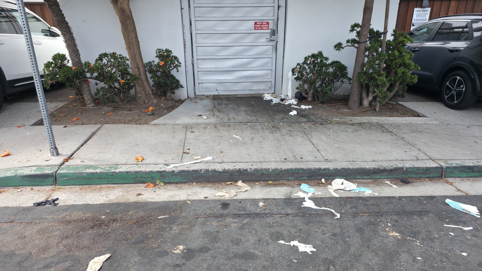 Napkins and food-service trash strewn across the walkway and into the street by the complex's back door.